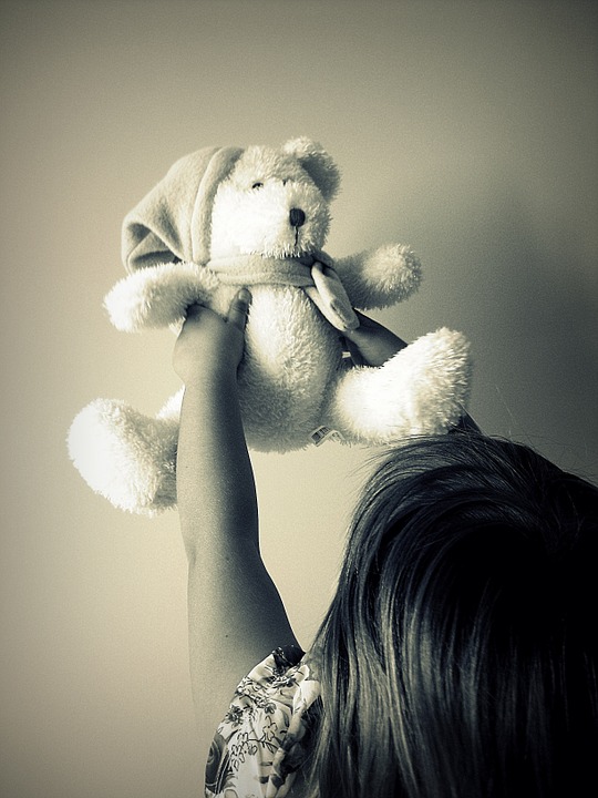girl holding up teddy bear